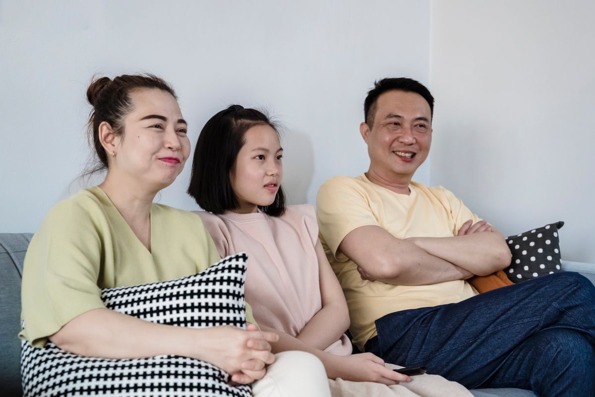 Ibu bapa dan anak perempuan mereka berehat di atas sofa di rumah