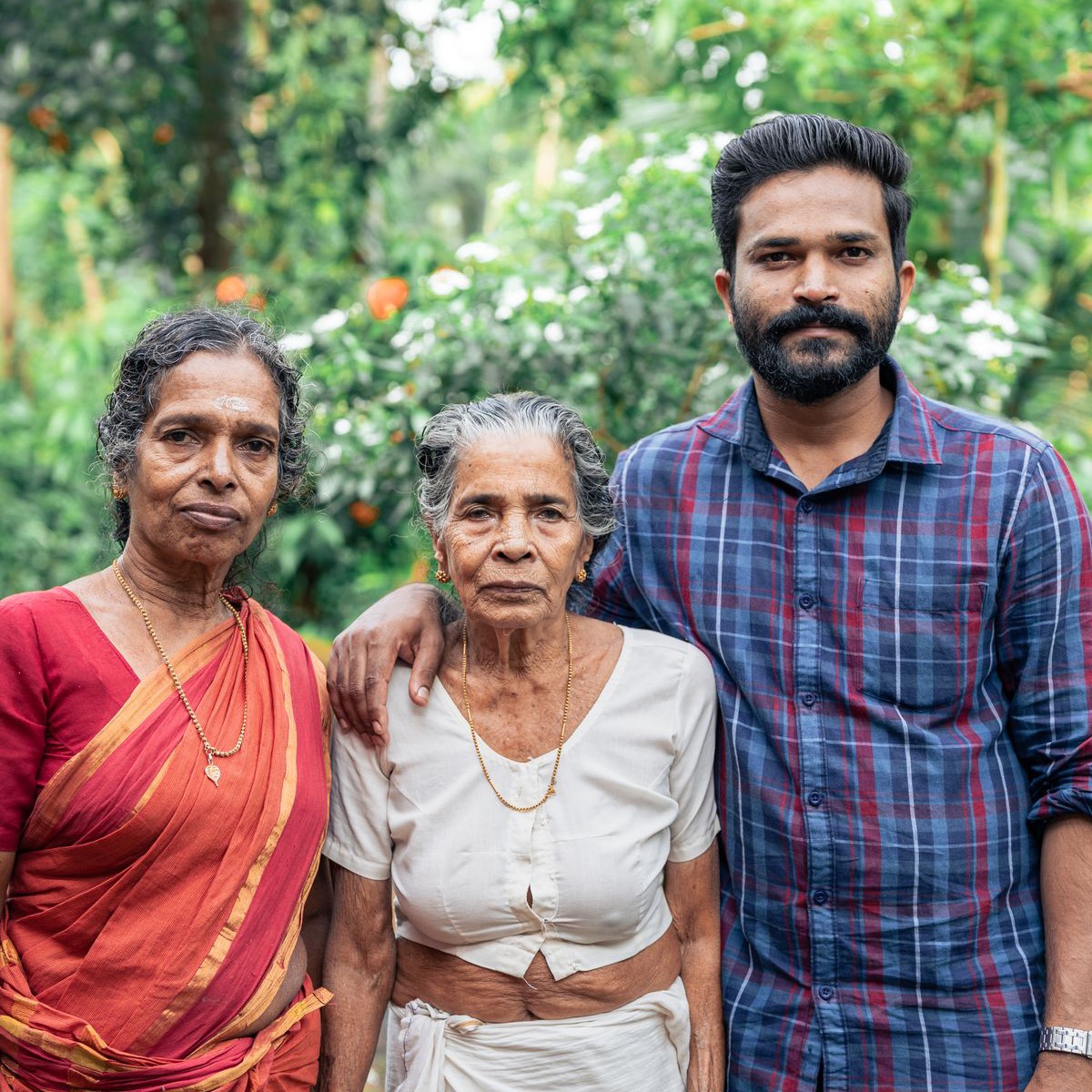 Keluarga India Malaysia berdiri bersama ibu tua mereka di halaman