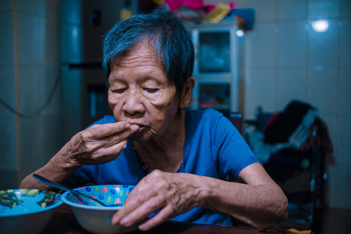 Lelaki warga emas menikmati makan malam di meja dapur